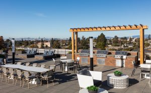 Image 55 - One BR Apartments in Oakland CA - Baxter on Broadway - Rooftop Grill Area with Three BBQs, Tables, and Chairs.